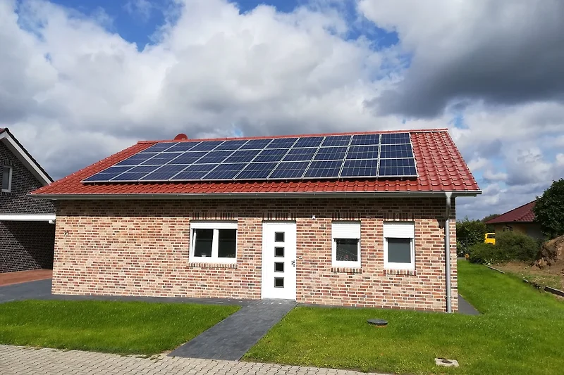 Das Ferienhaus Sonnenblume von vorne: Klinkerbau mit rotem Ziegeldach, weißer Haustür und Rasen vor dem Haus