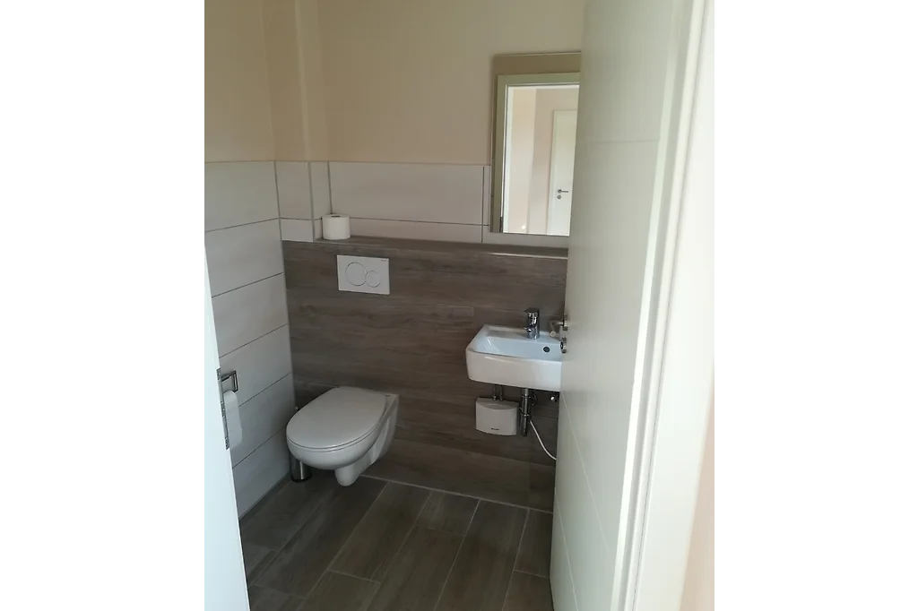 Gäste-WC mit Wand-WC, kleinem Waschbecken und Spiegel