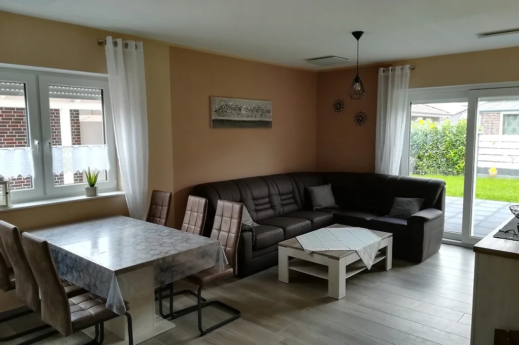 Wohnzimmer mit Ecksofa, Couchtisch, Esstisch und Schiebetür zum Garten